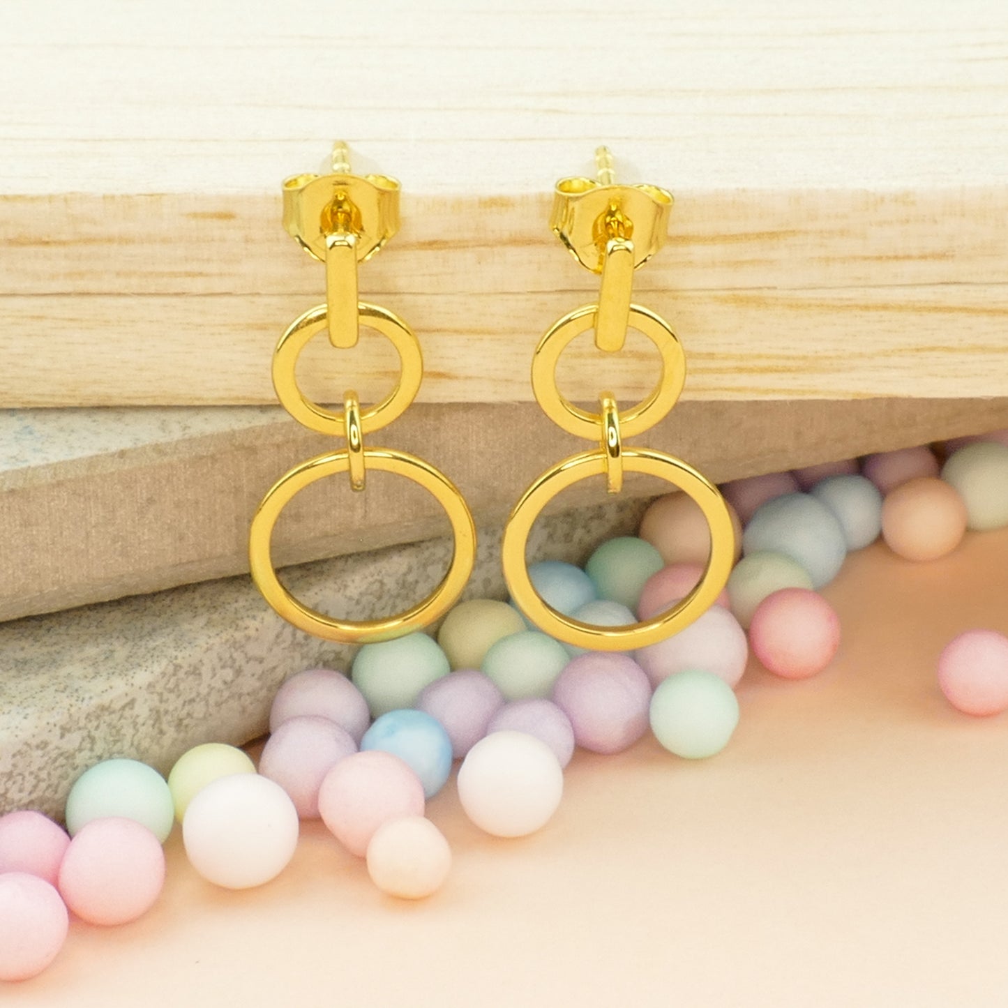 Close-up of double circle drop earrings in polished gold finish, showing the interlocking circle design and smooth texture